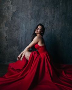 a woman in a red dress sitting on the floor