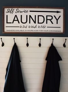 a sign that says self service laundry hangs on the wall next to two black towels