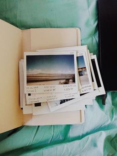 several polaroid photos are stacked on top of each other next to an open book