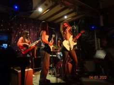 two women are playing guitars and singing into microphones while another woman plays guitar in the background