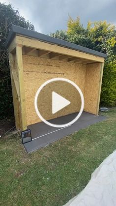 a wooden shed with the door open and a play button on it's side