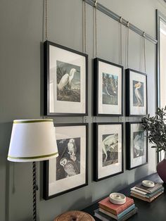 a living room with pictures hanging on the wall and a lamp in front of it