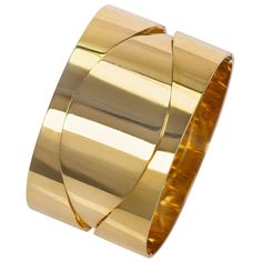 An 18 karat gold bangle bracelet, by Günter Wyss, c. 1960, Switzerland. The bracelet is stamped Günter Wyss Design, 750 with the artist's maker's mark. The inner circumference measures 7.0" and the bracelet measures 1.5" wide. Hinge Closure. Designed as two mirrored pieces joined to form one ultra sleek bangle, the undulating lines create a sense of moving parts when worn. Günter Wyss was born in 1934 in Zurich Switzerland and had an untimely death in 1971. Yet, Wyss had already become a leading Otto Kunzli, Gold Cuff Bangle, Zurich Switzerland, Gold Cuffs, Gold Bangle Bracelet, Gold Bangle, Maker's Mark, Cuff Bangles, Zurich