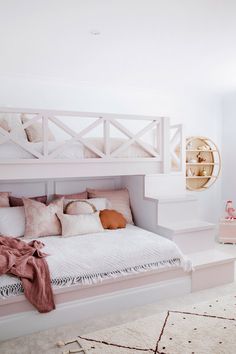 a white bed with pink pillows and blankets