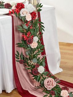 the table is decorated with red and pink flowers, greenery and candles on it