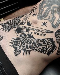 a man with tattoos on his stomach holding a knife