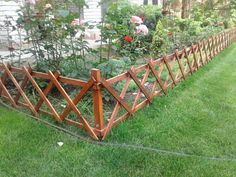 a wooden fence in front of a house with flowers growing on the side and behind it