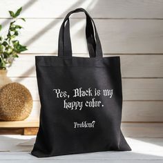 a black tote bag sitting on top of a table next to a potted plant