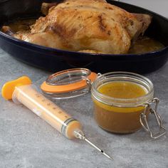 a chicken in a pan next to a bottle of mustard and a thermometer