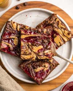 three pieces of brownie on a plate with raspberry sauce and peanut butter