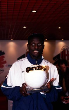 a man holding a soccer ball in front of his face and smiling at the camera