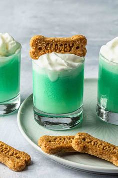 two glasses filled with green liquid and topped with whipped cream, pretzels and graham crackers