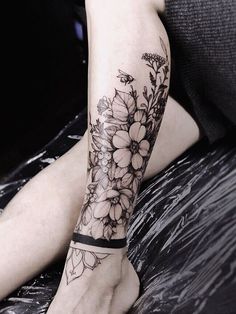 a woman's arm with flowers on it and a black band around the wrist