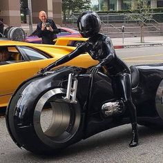 black and white photograph of a person on a motorcycle with other cars in the background