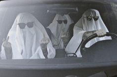 two people dressed in white sit behind the wheel of a car