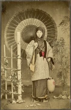 an old fashion photo of a woman in kimono and parasol holding a basket