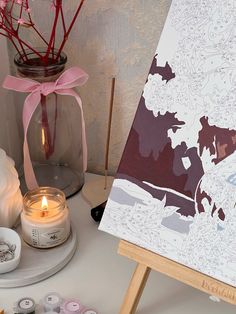 an easel with some candles on it next to a painting and other crafting supplies