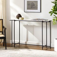 a black and white console table in a living room with a potted plant next to it