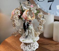 a bride and groom figurine sitting on top of a table next to a clock