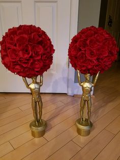 two vases filled with red flowers sitting on top of a wooden floor