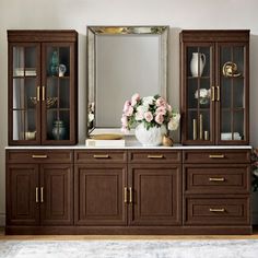 a large mirror sitting on top of a wooden cabinet next to a vase filled with flowers