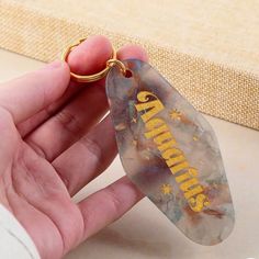 a person holding a keychain with the word grandma printed on it in gold