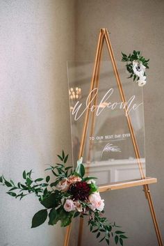 a wooden easel with flowers and greenery on it