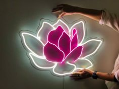 a man is holding up a neon sign with a flower on it's side