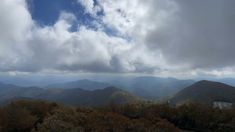 the mountains are covered in clouds as seen from an overlook point on a cloudy day