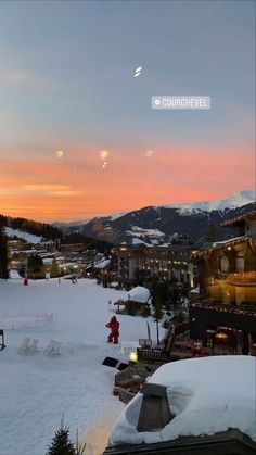 the sun is setting over a ski resort with snow on the ground and mountains in the background