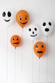 halloween balloons with faces and numbers hanging from strings in front of a white wall that says trick or treat