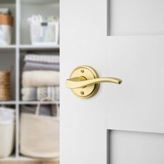 an open door with a handle on it in front of some shelves and linens