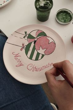 a person is holding a plate with an ornament on it that says merry christmas