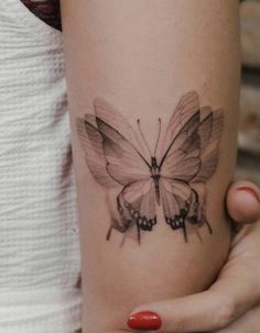 a woman's arm with a butterfly tattoo on the left side of her arm