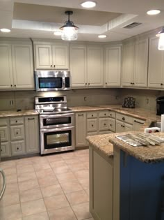 a kitchen with white cabinets and an island in the middle is lit by recessed lights