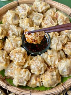 a plate full of dumplings with sauce and chopsticks