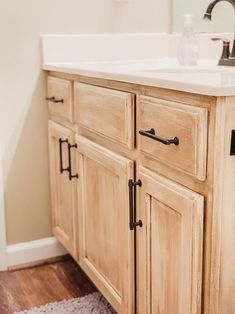 a bathroom vanity with white counter top and wooden cabinets