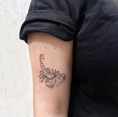 a woman's arm with a tattoo that has a small scorpion on it,