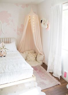 a white bed sitting in a bedroom next to a pink and white wallpapered wall