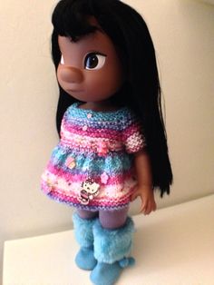 a doll with black hair wearing a colorful dress and blue pants on a white surface