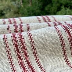 two red and white blankets sitting next to each other on a wooden table in front of trees