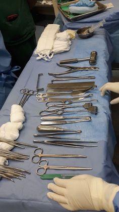 surgical instruments are laid out on a blue table with white gloves and gauze wrapped around them