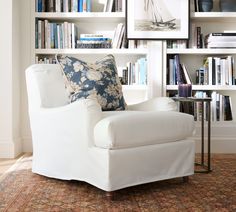 a white chair sitting in front of a book shelf filled with books