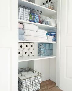 an organized closet with toilet paper, towels and other items in baskets on the shelves