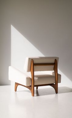 a white chair sitting in the middle of a room next to a wall with sunlight streaming through it