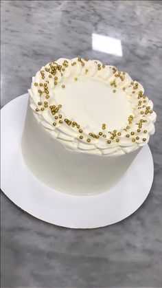 a white cake with gold sprinkles sitting on top of a countertop