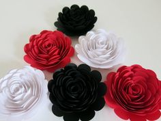 six paper flowers are arranged on a white surface, one is red and the other is black