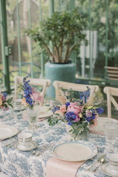 the table is set with blue and pink flowers