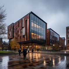 people are walking in front of a building on a rainy day