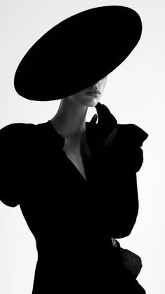 a woman in a black dress and large hat